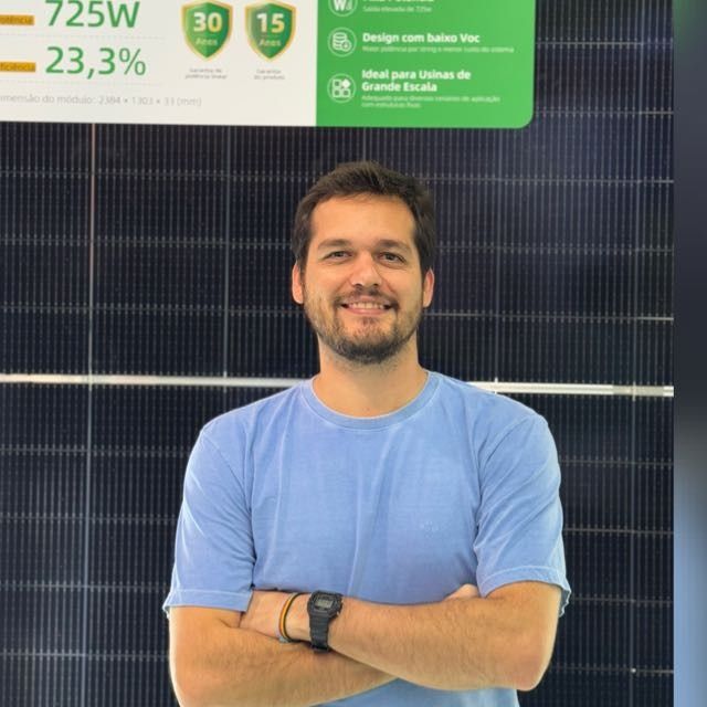 Matheus Grandolpho, de braços cruzados, em frente a um painel solar